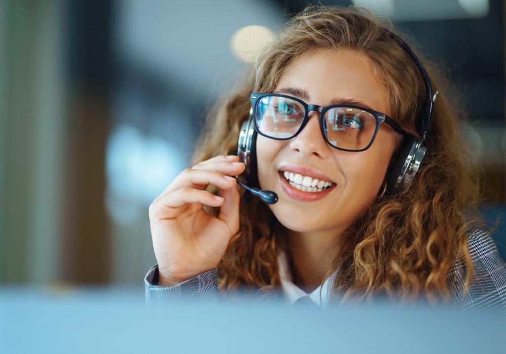 Call center agent with headset working on support hotline in modern office. Video conference.
