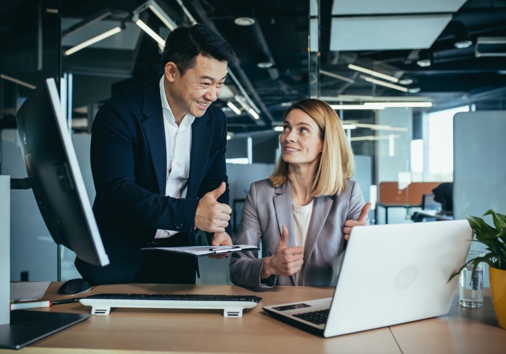 two business people consulting on a project looking at computer monitor screen sitting the office